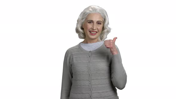 Smiling Senior Woman Pointing Thumb Behind Her Back alt