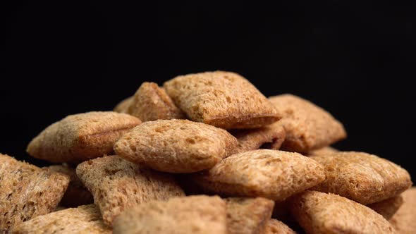 Crispy chocolate pads rotation in macro on black background. Cereal dessert for a fast breakfast alt