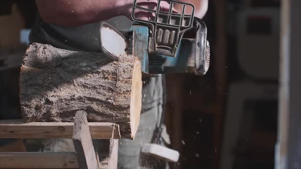 Man Is Sawing a Wood with an Electrical Chainsaw at Carpentry, Slow Motion