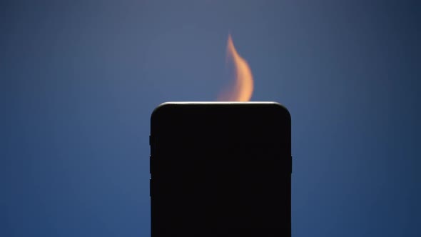 Flame from silhouette of smartphone on blue background