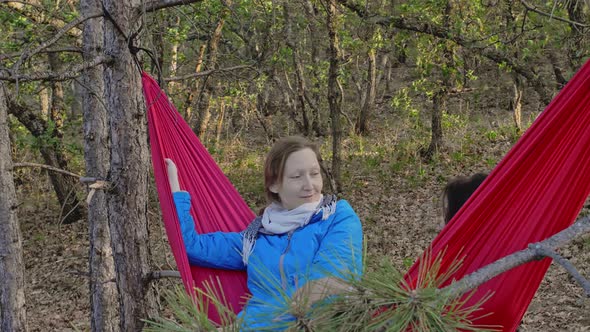 Two Friends Laugh and Talk While Lying on a Hammock in the Middle of the Forest The Idea of a alt
