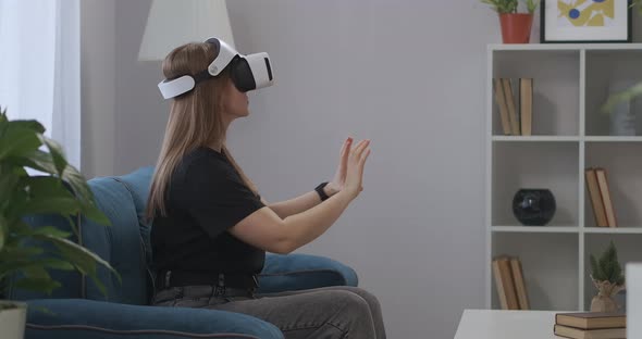 Woman with Headmounted Display Is Having Fun at Home at Weekends Viewing Pictures or Video Zooming alt