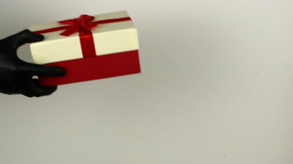 A man gives a woman a gift box in black COVID 19 gloves. Christmas shopping alt