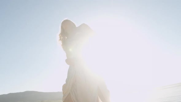 Dancing Blond Woman In Gold On Sunlit Beach alt