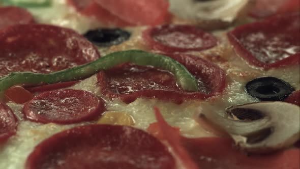 An almost cooked pizza is cooking while it's rotating in the oven. Close up.