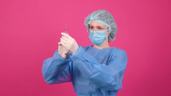Professional Female Doctor Holds a Syringe with a Vaccine on a Pink Background alt