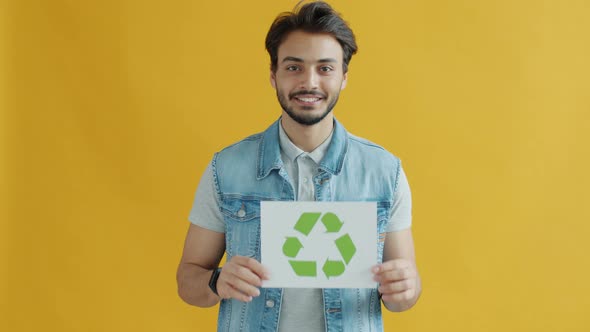 Cheerful Indian Guy Holding Recycling Symbol Promoting Ecological Protection and Smiling alt