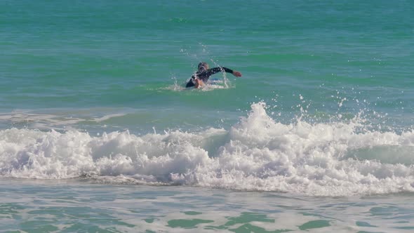 Surfer Lies on the Surf and Swims Against the Wave
