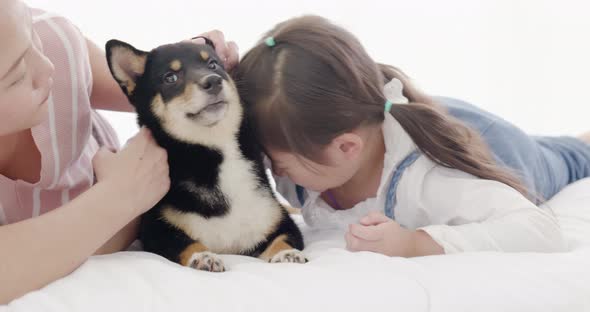 Mother and daughter playing with black dog on bed (7)