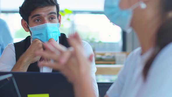 business meeting Freelance caucasian male and asian female putting protective face mask alt