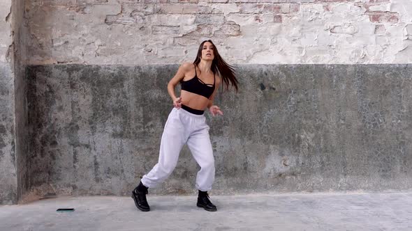 Female hip-hop dancer performing in front of flaking wall