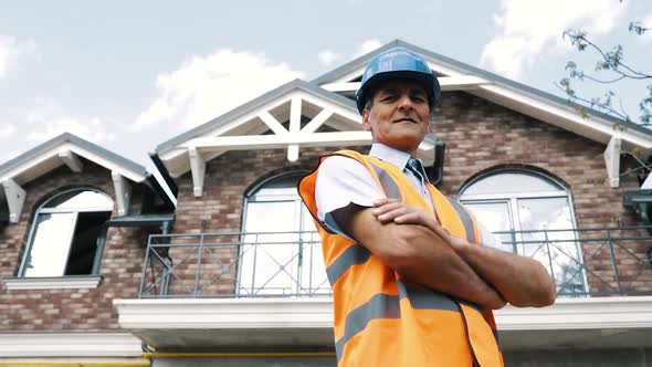 Male Builder Contractor Stands with His Crossed Hands Smiling and Looking Away alt