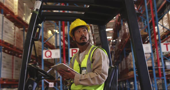 Young man working in a warehouse sitting in forklift 4k alt