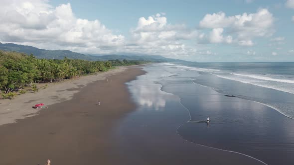 People playing in the sandy, shallow waters of Playa Linda (Matapalo), a hidden beach on the Central alt