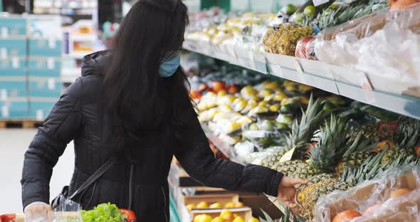 Woman in Face Mask is Buying Pineapples Fruits in Supermarket