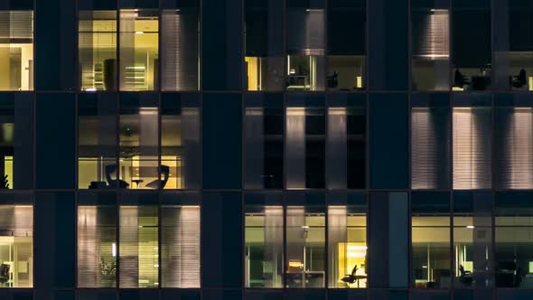 Window of the Multistorey Building of Glass and Steel Lighting and People Within Timelapse alt