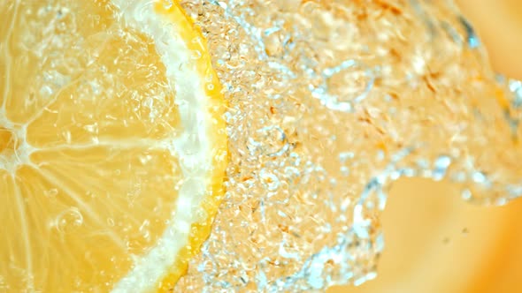 Super Slow Motion Shot of Splashing Water on Rotating Lemon Slice at 1000Fps. alt