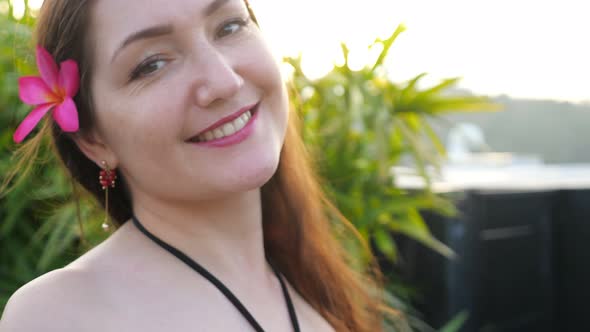 Brunette with Flower in Long Loose Hair Poses with Smile alt