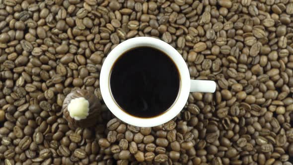 A Cup Of Black Coffee And Chocolate On A Background Of Rotating Coffee Beans.