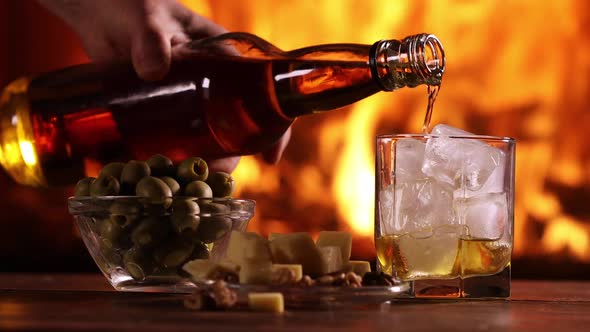 A Man's Hand Pours Whisky From a Bottle Into a Glass