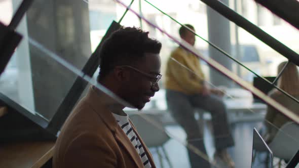 Handsome young African American business man working on laptop while sitting at stairs