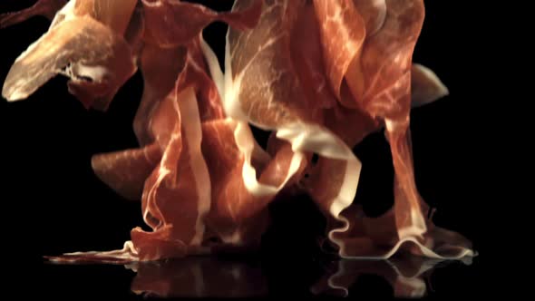 Super Slow Motion Pieces of Fragrant Spanish Ham Fall on the Table alt