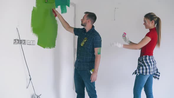 Lady in Dirty Clothes Proposes to Man Painting Wall in Room alt