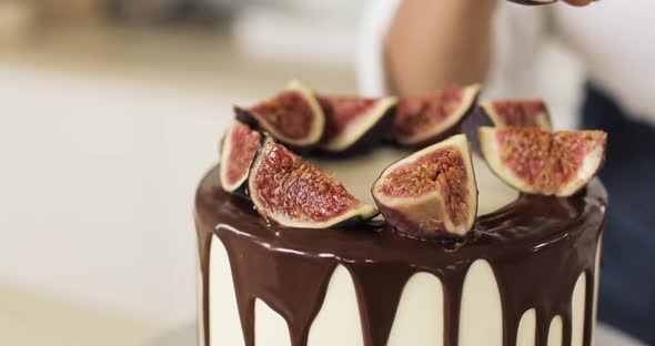 The Pastry Chef Decorates a Caramel Cake or Cheesecake with Figs alt