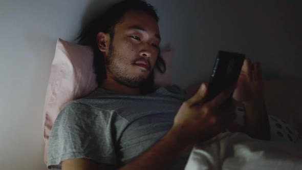 Young Asian men using a smartphone browsing web and scroll through social media feeds.