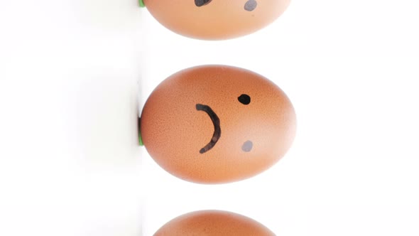 Vertical video, Dolly shot of Emotion painted eggs isolated on white background.