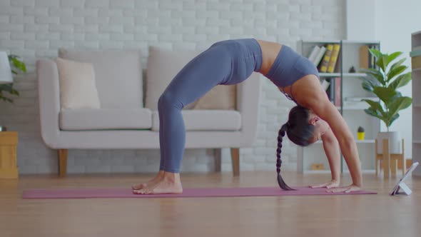 Asian woman look laptop practice yoga bridge online course at home alt