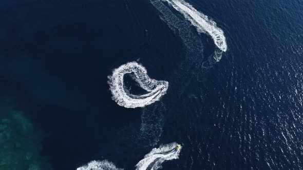 aerial view of a fast speedboats driving around in the circle and making beautiful shapes 