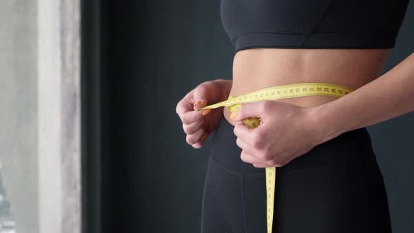 Fitness Woman With Tape Measure Showing Her Waist alt