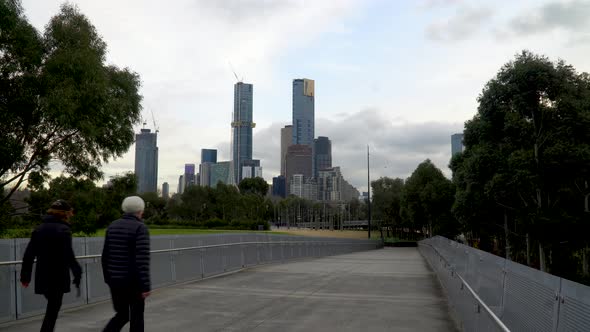 A couple walk down a Melbourne walkway with the skyline in the background - exercise during the coro alt