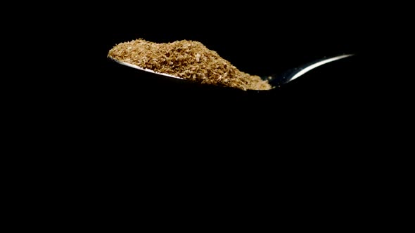 Seasoning Falling Down From Teaspoon Isolated on Black Background Slow Mo