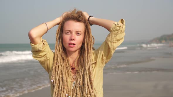 Portrait of a Young Woman with Dreadlocks Hair on a Background of the Sea alt