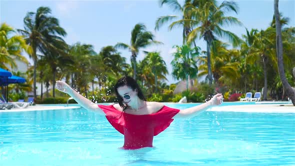 Beautiful Young Woman Relaxing in Swimming Pool. Happy Girl in Outdoor Pool at Luxury Hotel alt