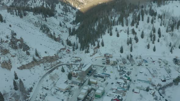 Aerial Drone Shot Descending Towards Small Mountain Town in Snowy Valley