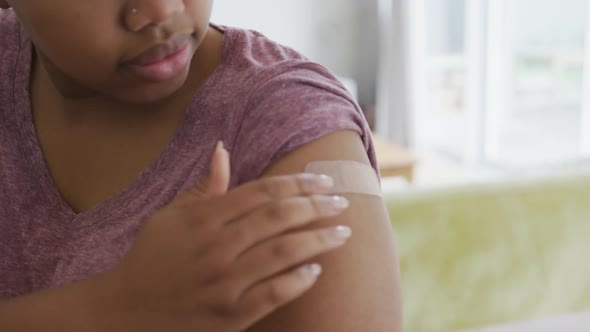Happy african american woman with bandage on her arm after vaccination alt