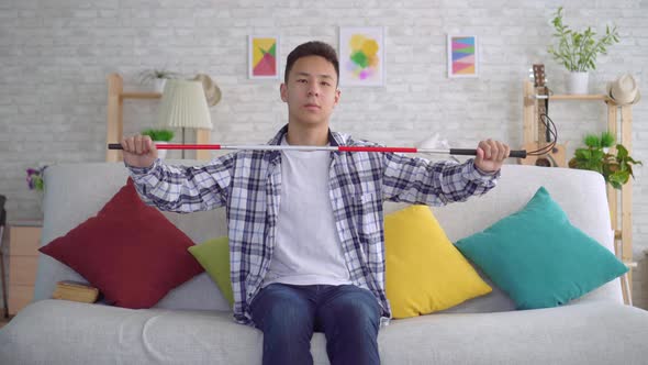 Blind Asian Young Man Sitting on Sofa in Living Room alt