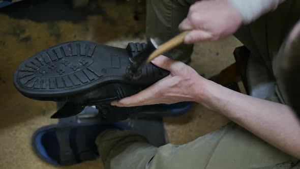 Top View Shoemaker Knocking with a Hammer on the Sole of the Shoe