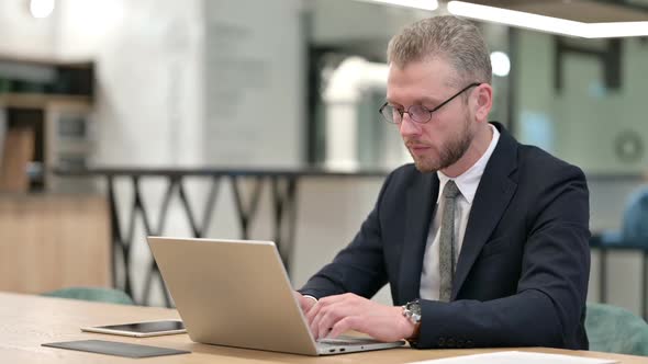 Serious Young Businessman with Laptop Looking at Camera alt