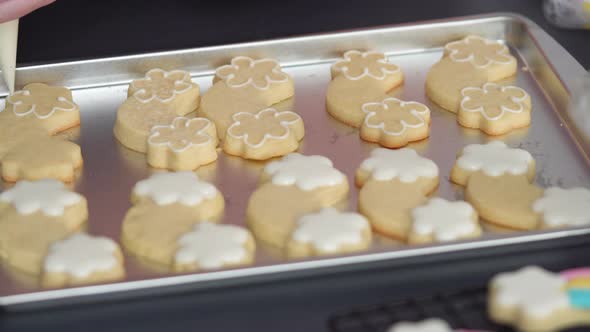 Step by step. Decorating unicorn theme sugar cookies with royal icing on baking sheet. alt