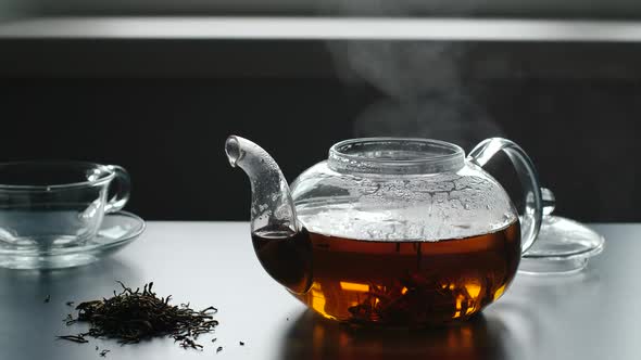 Steam from a teapot on a table, Near is tea crop and glass cup