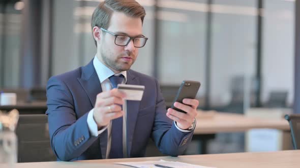 Businessman Reacting to Loss on Smartphone in Office alt