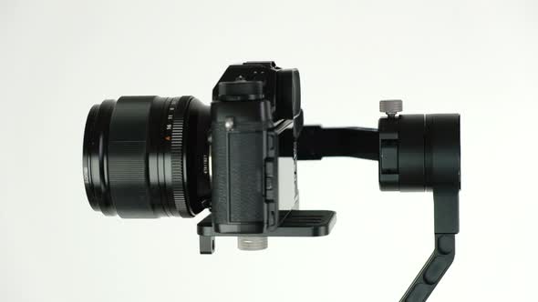 Electronic steadycam with digital camera rotates on white background. alt
