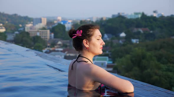 Pretty Lady in Swimsuit Looks and Smiles Relaxing in Pool alt