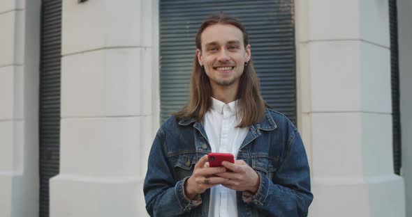 Portrait of Cheerful Young Guy with Earrings Raising Head and Looking To Camera. Millennial Long alt