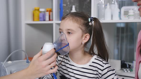 Portrait of a Woman Pediatrician and a Little Girl with an Inhalation Mask From a Nebulizer alt