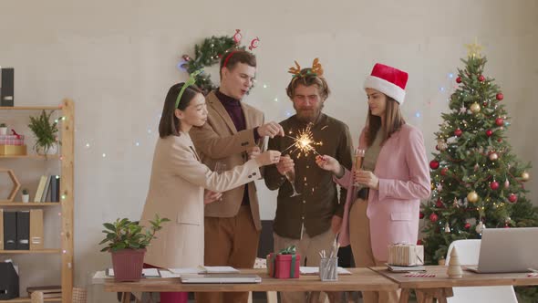 Cheerful Colleagues with Sparklers Celebrating Christmas in Office alt